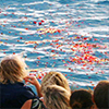 Friends and family look out onto the Pacific Ocean from a boat while on a burial at sea ceremony.