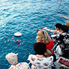 Friends and family honor a loved one with a floral wreath during an ash scattering at sea ceremony.